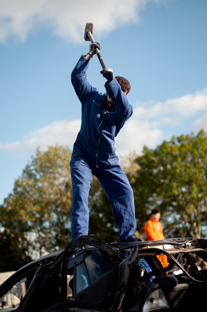 Photo by Giu Vicente a man holding a hammer up to a car